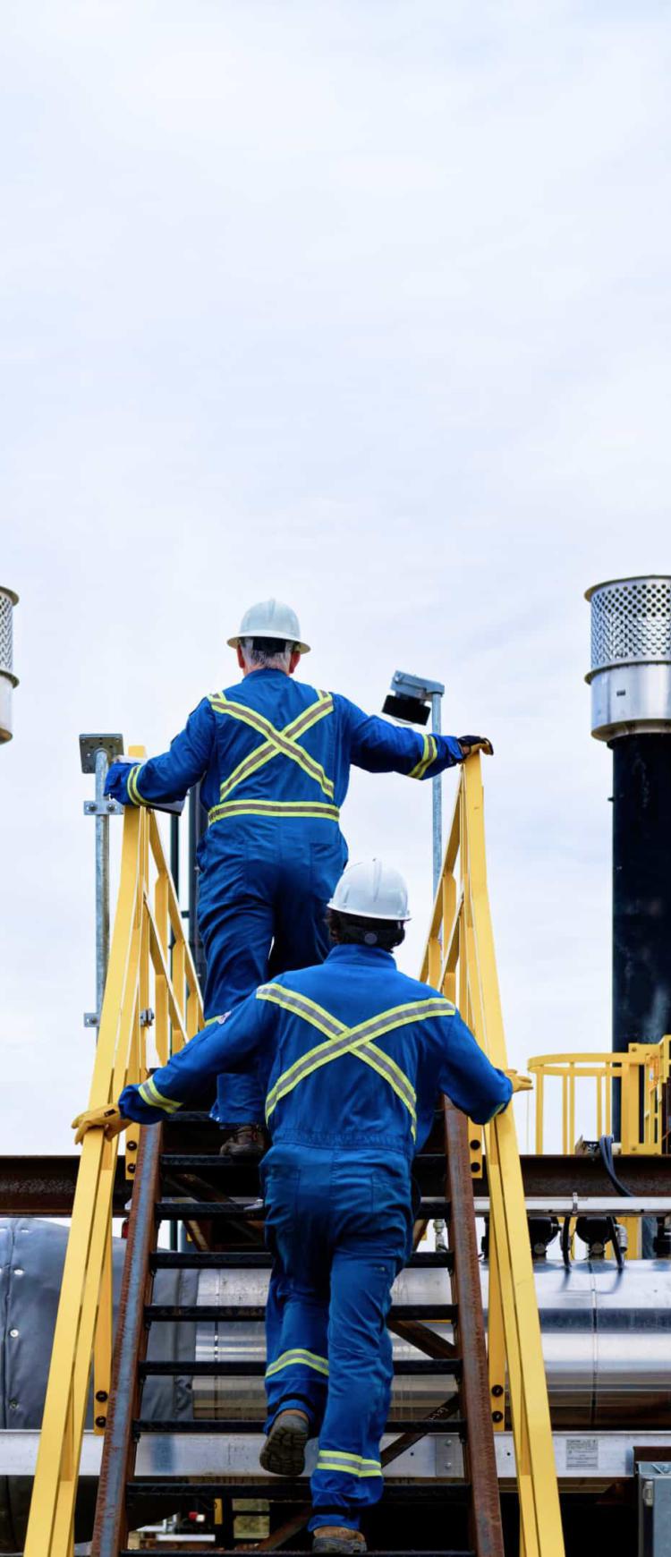 Construction workers walking up stairs of an oil and gas plant